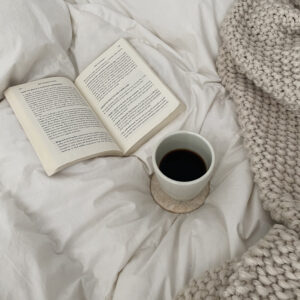 coffee and book on bed with blanket